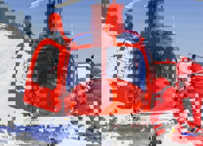 Rescue helicopter landed on a snowy mountainside with two emergency responders