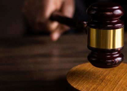 Judge’s gavel striking a wooden sound block in a courtroom setting