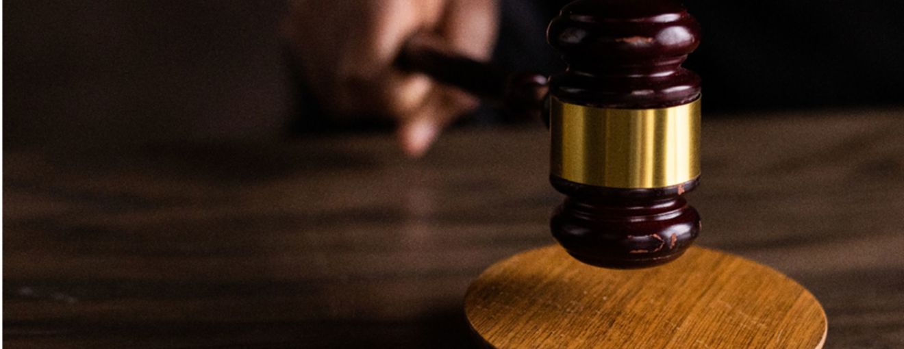 Judge’s gavel striking a wooden sound block in a courtroom setting