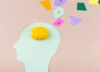 illustration of a human head silhouette with a yellow brain model inside and colourful geometric shapes emerging from it