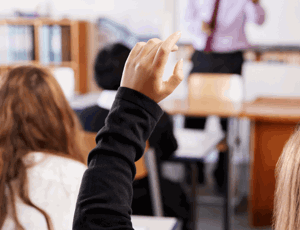 Students in a classroom with their hands raised