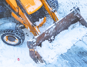 Front loader clearing snow on a snowy road surface